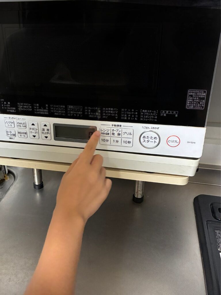 中学生の子どもが電子レンジにナッシュを入れ、温め時間を入力するところ。